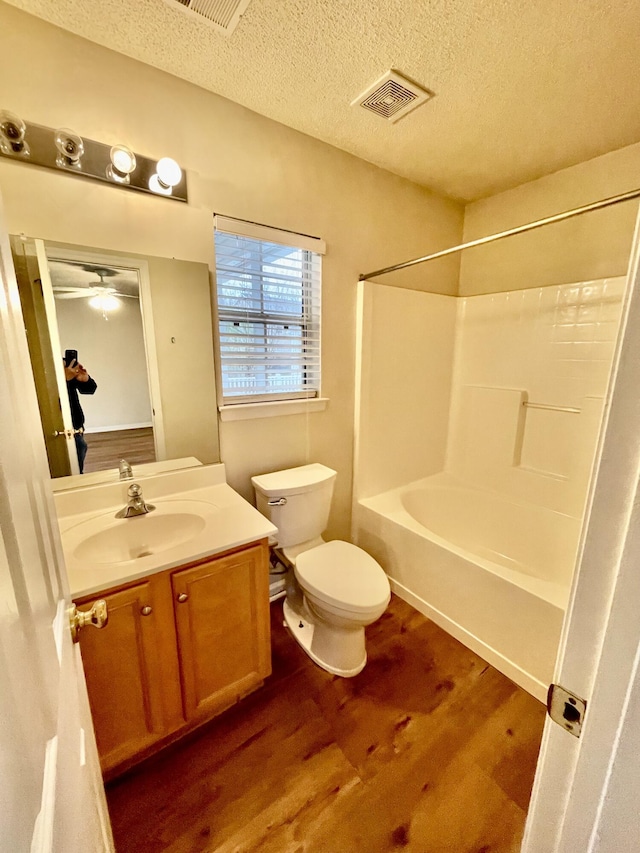 bathroom with visible vents, toilet, a textured ceiling, wood finished floors, and vanity