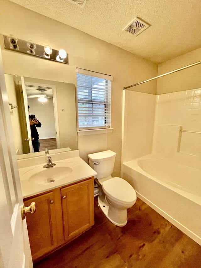 bathroom featuring visible vents, toilet, shower / bath combination, vanity, and a textured ceiling