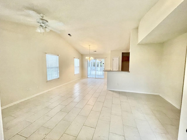 empty room with lofted ceiling, ceiling fan with notable chandelier, baseboards, and visible vents