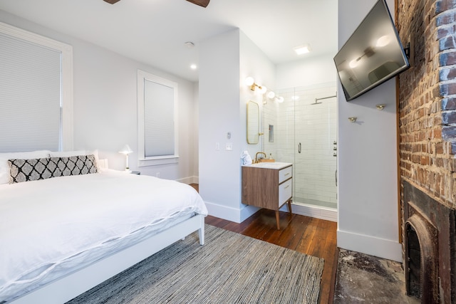 bedroom featuring dark wood-style flooring, a sink, baseboards, and ensuite bathroom