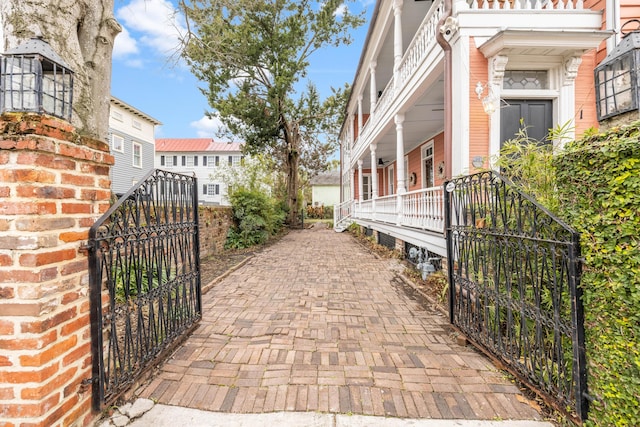 view of property exterior featuring a fenced front yard, a gate, a porch, and brick siding