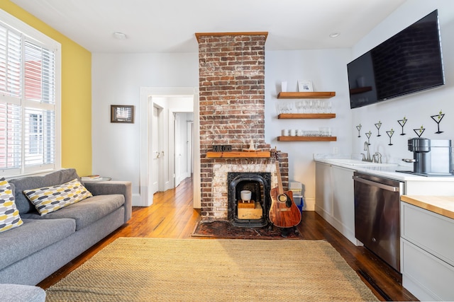 living room with dark wood-style floors, indoor wet bar, a fireplace, and baseboards