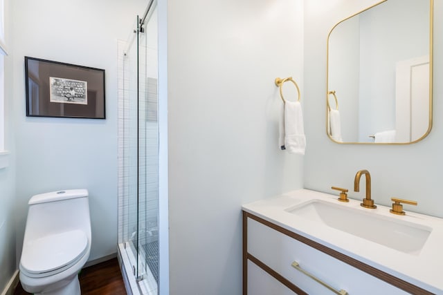 bathroom with vanity, wood finished floors, a shower stall, and toilet