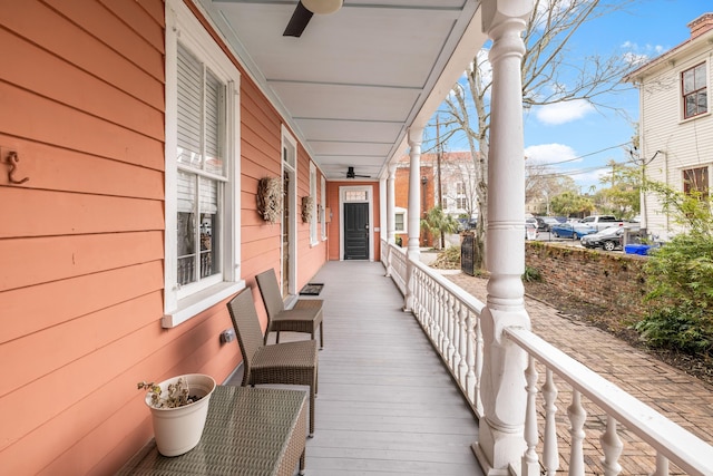 wooden terrace featuring covered porch and a ceiling fan