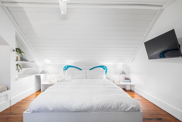 bedroom with vaulted ceiling, baseboards, and wood finished floors