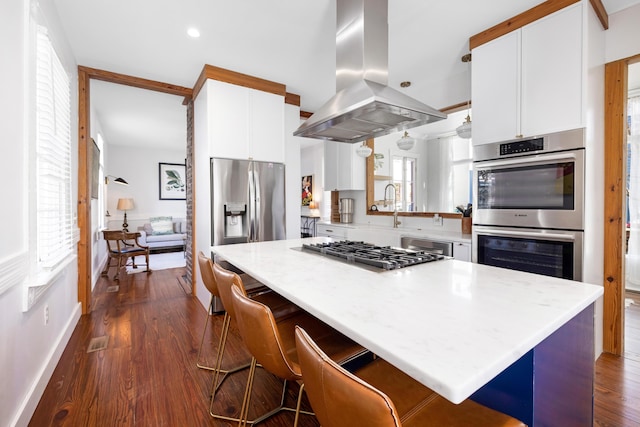 kitchen with island range hood, white cabinets, light countertops, appliances with stainless steel finishes, and dark wood finished floors