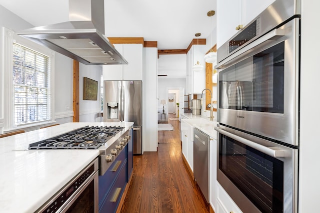 kitchen with white cabinetry, light countertops, wall chimney range hood, appliances with stainless steel finishes, and dark wood-style floors