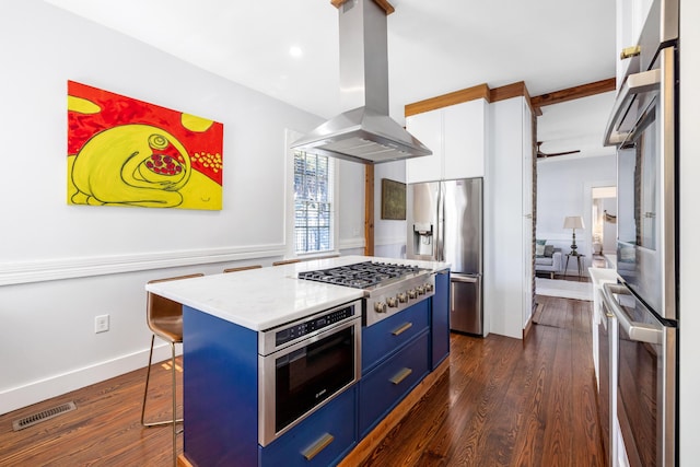 kitchen featuring a breakfast bar area, blue cabinets, visible vents, appliances with stainless steel finishes, and island exhaust hood