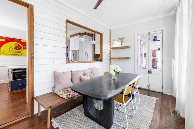 dining area featuring a ceiling fan, visible vents, crown molding, and wood finished floors