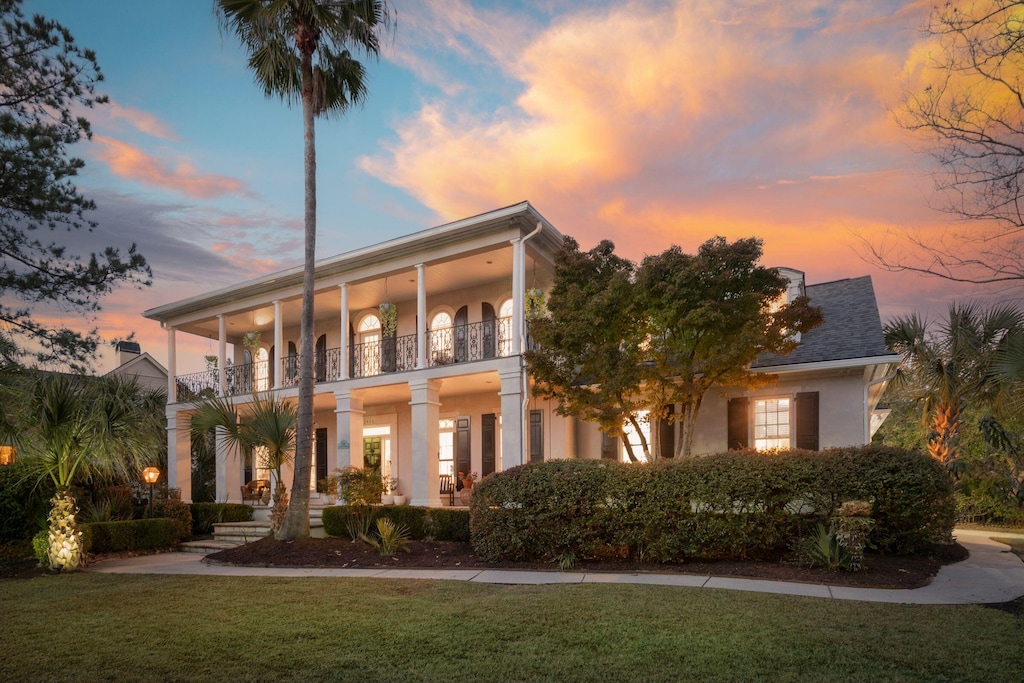 view of front of home featuring a lawn and a balcony