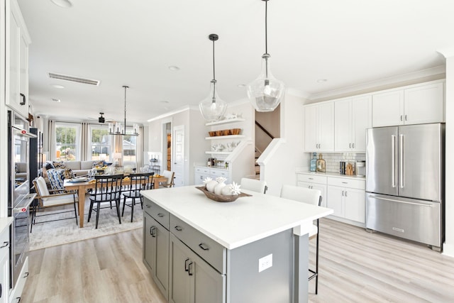 kitchen featuring stainless steel appliances, tasteful backsplash, gray cabinetry, a kitchen island, and light wood-type flooring