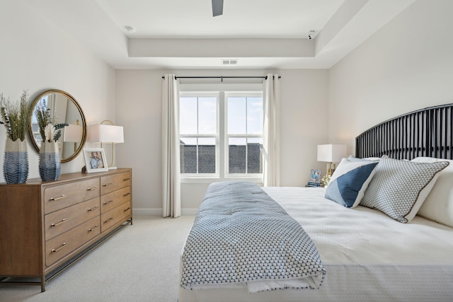 bedroom featuring baseboards, a raised ceiling, visible vents, and light colored carpet