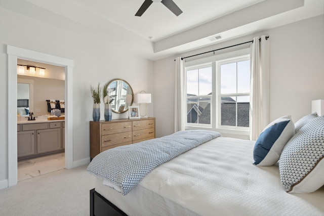 bedroom with baseboards, connected bathroom, visible vents, and light colored carpet