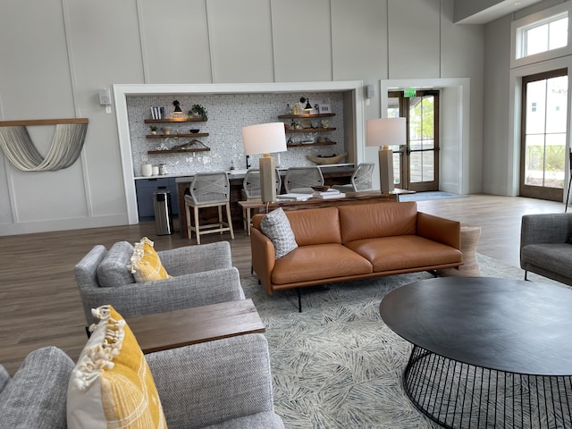 living room featuring a decorative wall, a towering ceiling, and wood finished floors