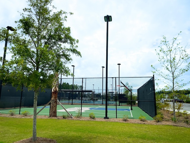 view of tennis court with community basketball court, a lawn, and fence