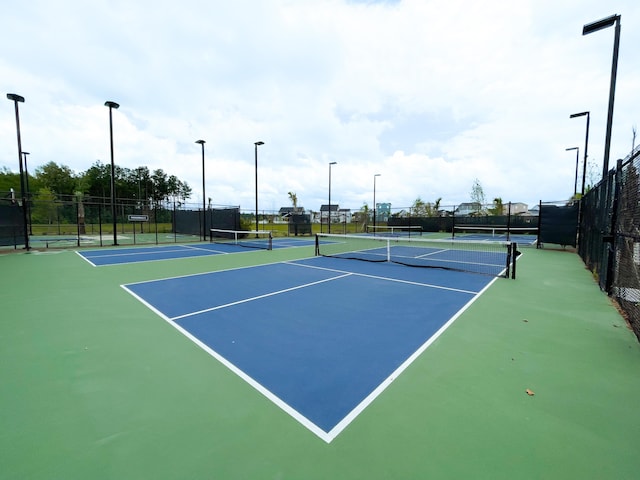 view of tennis court featuring community basketball court and fence