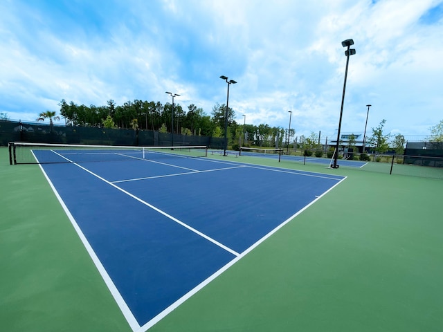 view of tennis court with community basketball court and fence