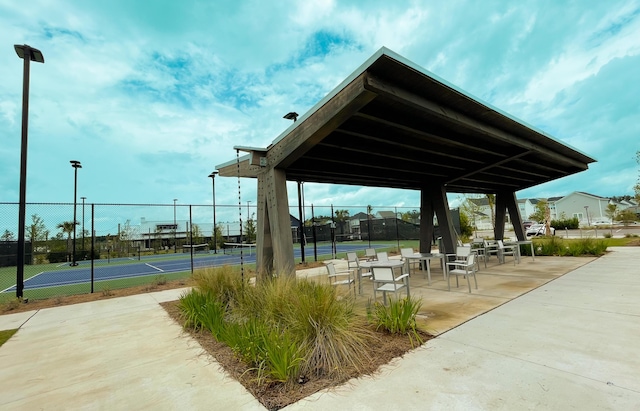 surrounding community with a tennis court and fence