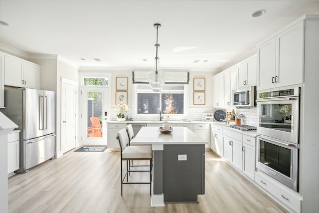 kitchen with decorative backsplash, a center island, stainless steel appliances, light countertops, and white cabinetry