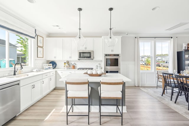 kitchen featuring stainless steel appliances, a sink, white cabinetry, and a center island