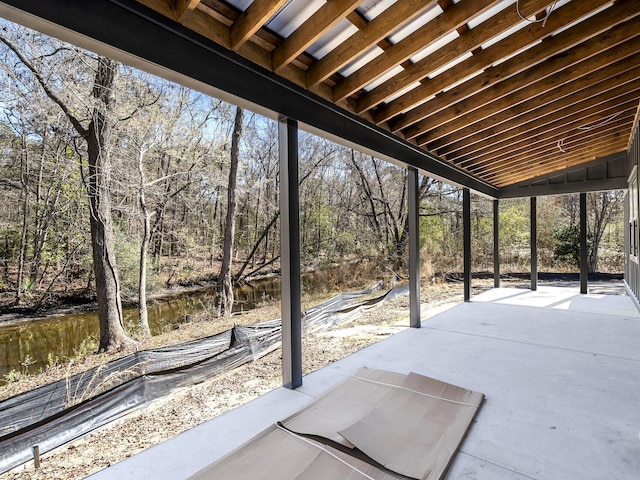 view of patio featuring a water view and a forest view