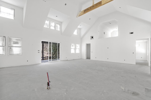 unfurnished living room with plenty of natural light, visible vents, and high vaulted ceiling