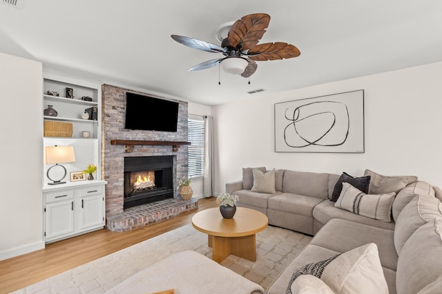 living room featuring a fireplace, ceiling fan, and light hardwood / wood-style flooring