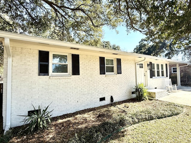 view of front of home with a patio, brick siding, and crawl space