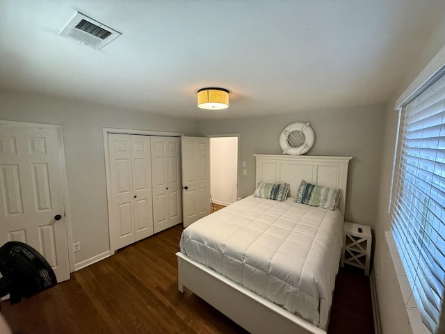 bedroom featuring dark wood-type flooring, a closet, visible vents, and baseboards