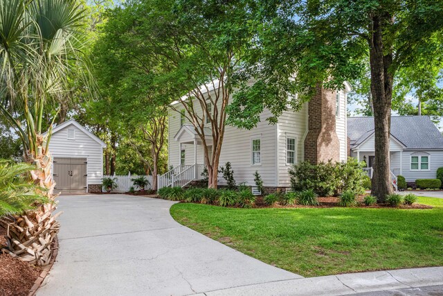 1514 Village Sq, Mount Pleasant, SC 29464 - view of property hidden behind natural elements with an outbuilding, a front lawn, a detached garage, a chimney, and concrete driveway