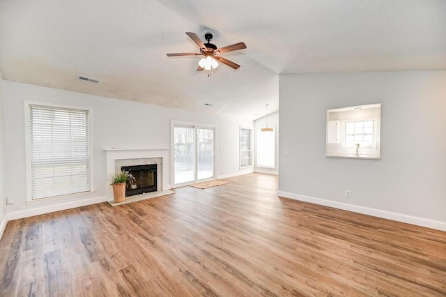 unfurnished living room with ceiling fan, lofted ceiling, a fireplace, and light hardwood / wood-style floors