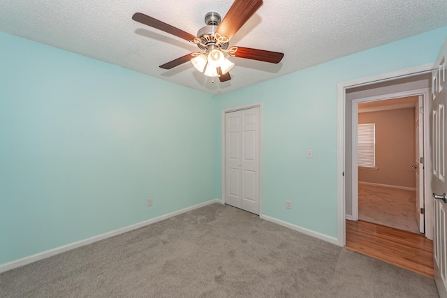 unfurnished bedroom with ceiling fan, a closet, light colored carpet, and a textured ceiling