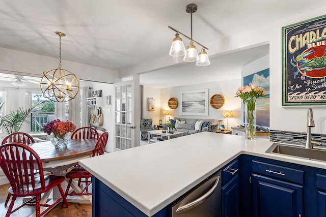 kitchen featuring hardwood / wood-style floors, stainless steel dishwasher, a chandelier, sink, and blue cabinetry