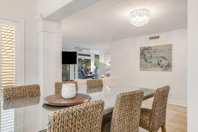 dining area featuring crown molding, ceiling fan with notable chandelier, visible vents, wood finished floors, and baseboards