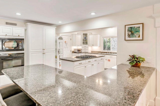 kitchen featuring visible vents, a sink, black oven, stainless steel gas cooktop, and built in microwave