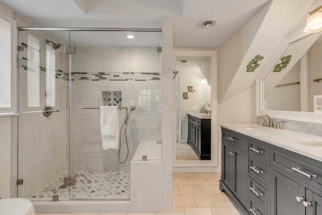 full bathroom featuring visible vents, a sink, a shower stall, double vanity, and tile patterned floors