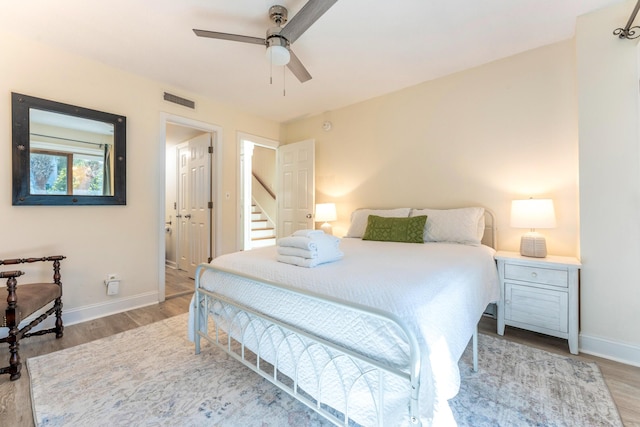 bedroom featuring visible vents, baseboards, ceiling fan, and wood finished floors