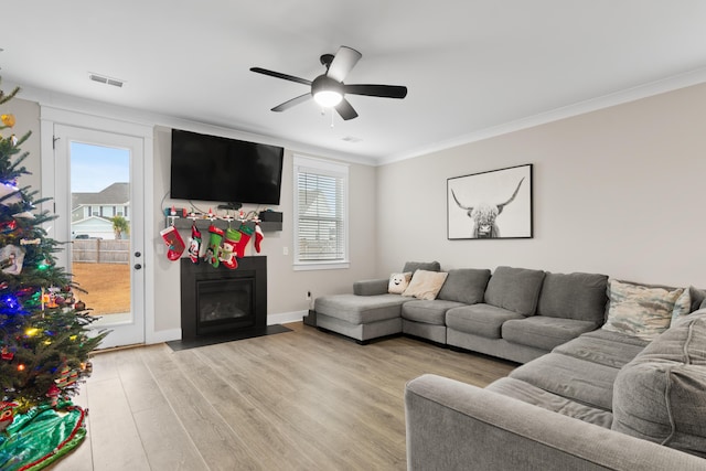 living room featuring light hardwood / wood-style floors, ceiling fan, and crown molding