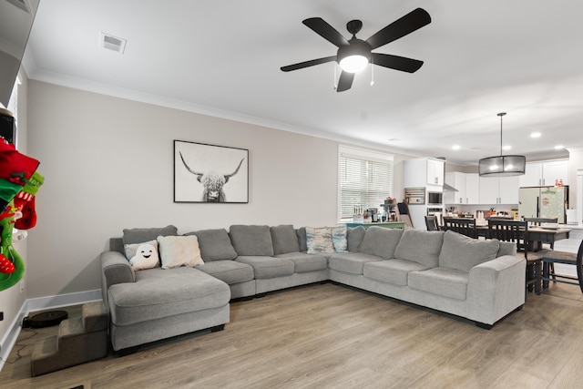 living room featuring ceiling fan, ornamental molding, and light hardwood / wood-style flooring