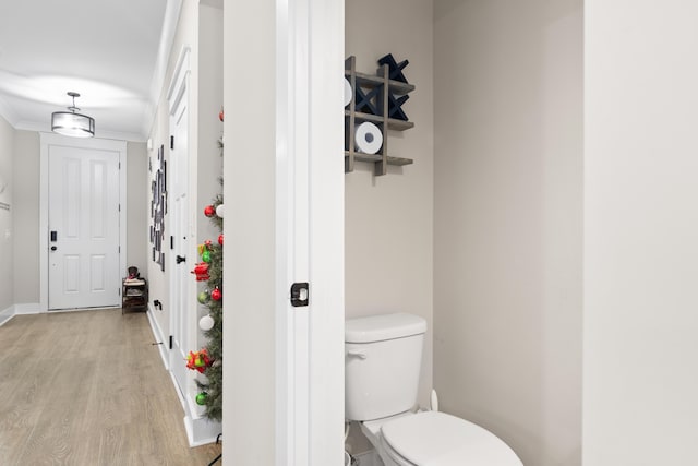 bathroom with crown molding, hardwood / wood-style floors, and toilet