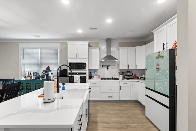 kitchen with fridge, white cabinets, wall chimney range hood, tasteful backsplash, and gas cooktop