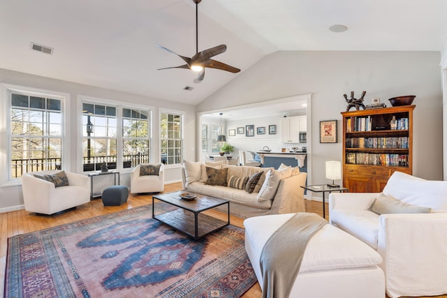 living area featuring vaulted ceiling, ceiling fan, wood finished floors, and visible vents