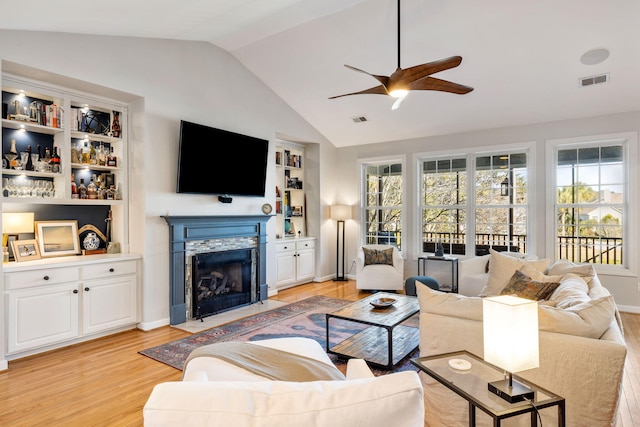 living room featuring a fireplace with flush hearth, lofted ceiling, visible vents, and light wood-style floors