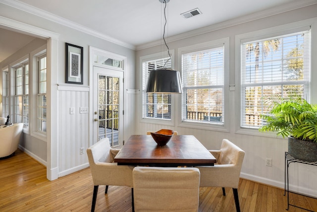 dining area with light wood-type flooring, baseboards, visible vents, and ornamental molding