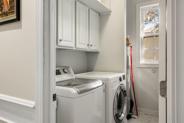 washroom featuring cabinet space, baseboards, and separate washer and dryer