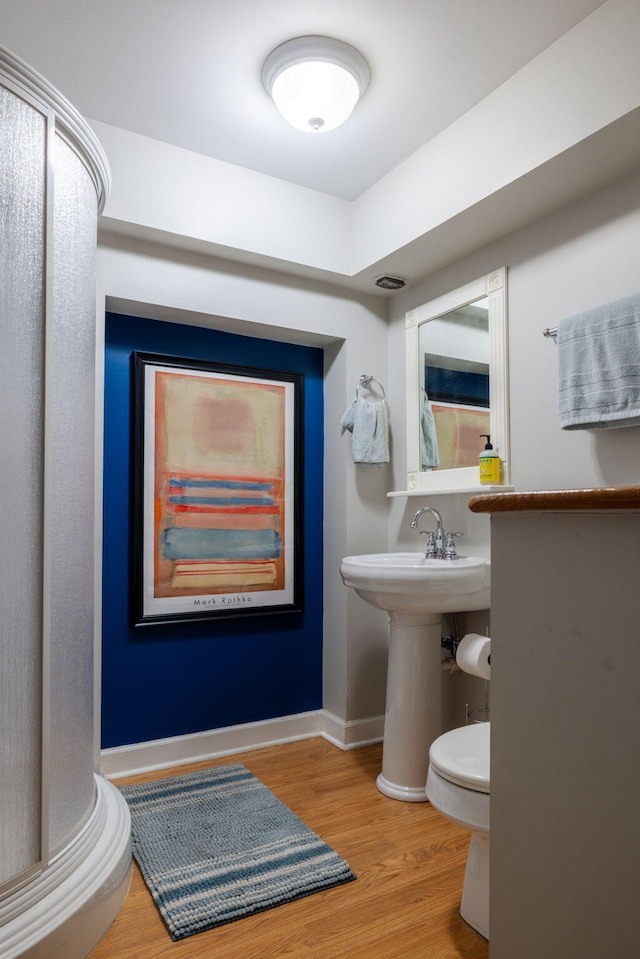 bathroom featuring toilet, a sink, visible vents, wood finished floors, and baseboards