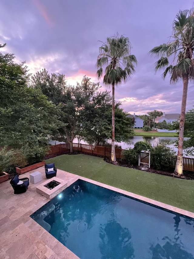 view of pool with a patio area, a fenced backyard, a water view, and a fire pit