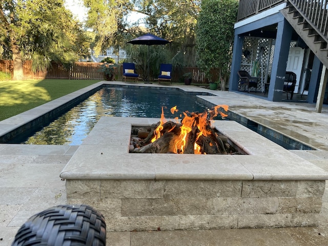 view of swimming pool with a fenced backyard, a fire pit, a lawn, a fenced in pool, and a patio area