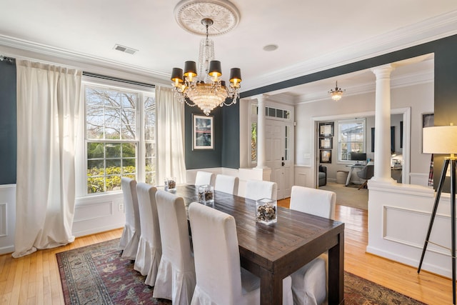 dining space with decorative columns, visible vents, light wood-style flooring, and a notable chandelier