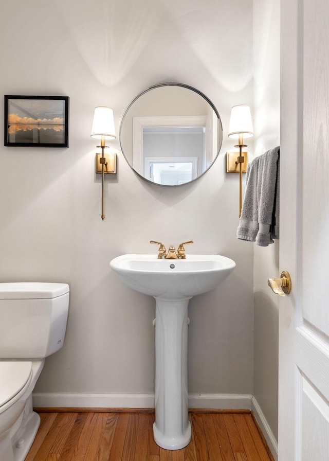 half bath featuring toilet, baseboards, and wood finished floors